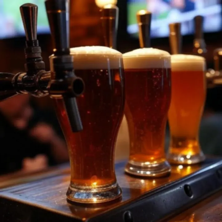 Zbliżenie na krany piwne i kufle wypełnione złocistym piwem w barze sportowym.